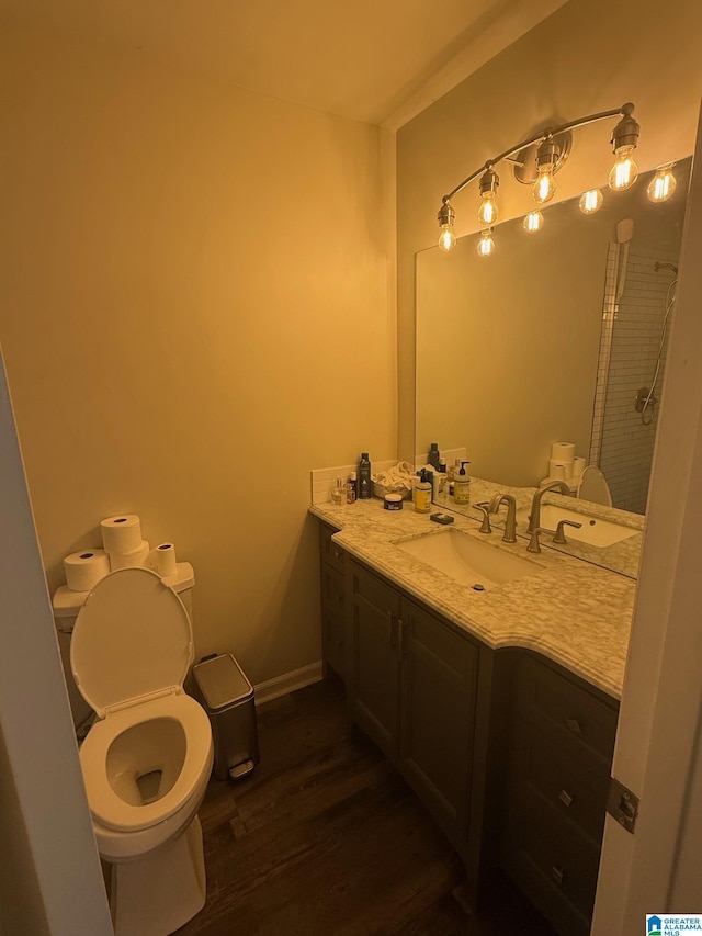 bathroom featuring toilet, wood finished floors, vanity, and baseboards