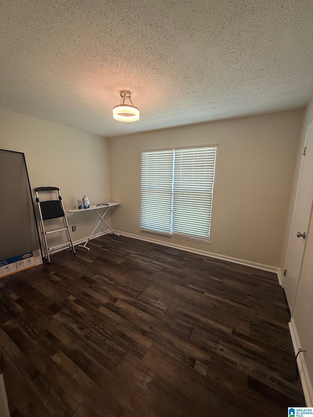 interior space with dark wood-style floors, a textured ceiling, and baseboards