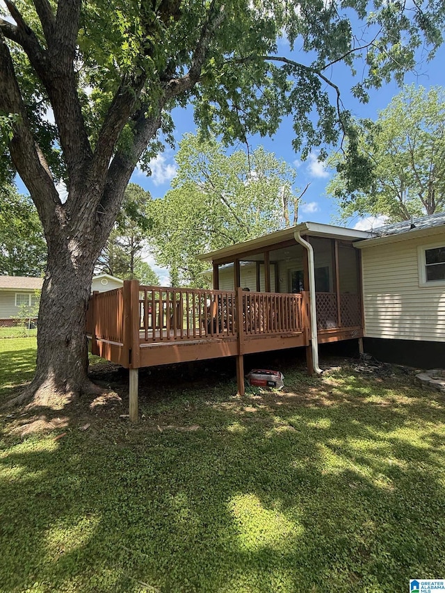 rear view of property with a wooden deck and a lawn