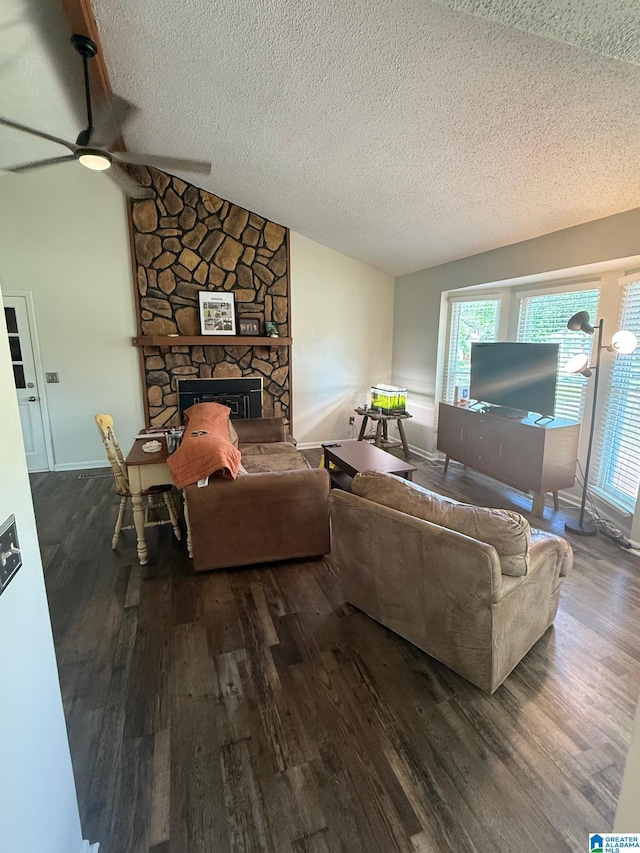 living area with a textured ceiling, ceiling fan, dark wood-style flooring, vaulted ceiling, and a fireplace