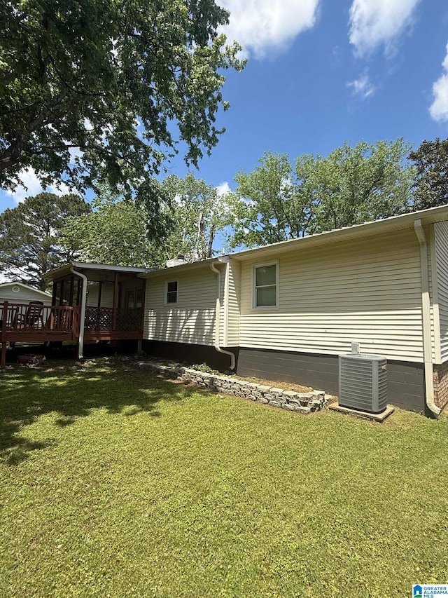 back of property with central AC, a yard, and a sunroom