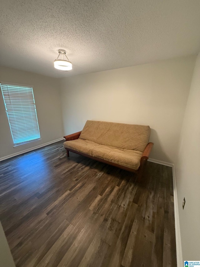 living area featuring dark wood-style floors, a textured ceiling, visible vents, and baseboards