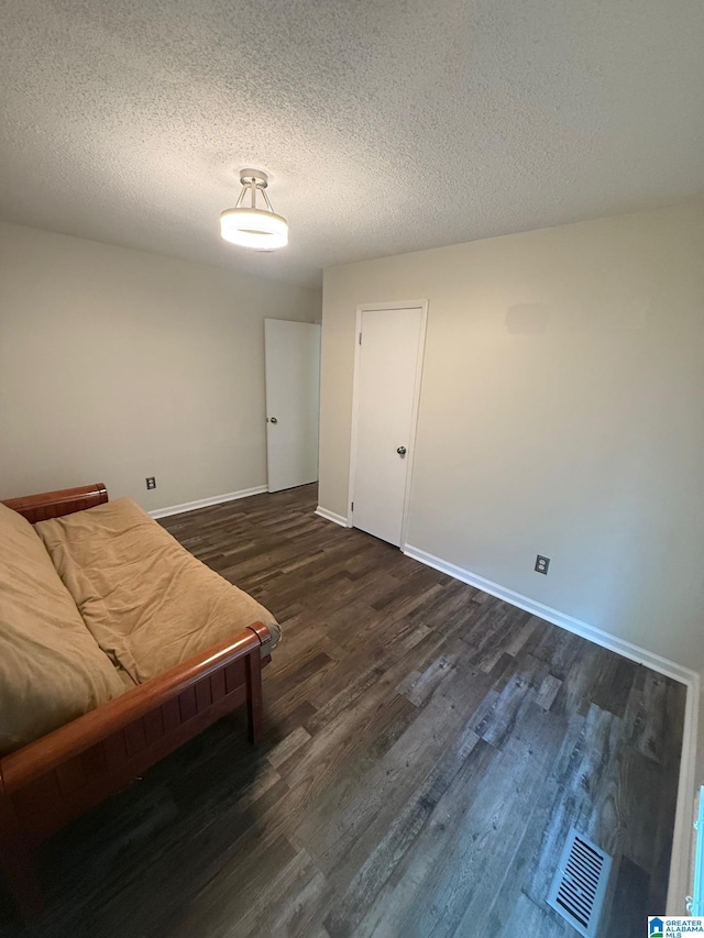 living area with baseboards, visible vents, a textured ceiling, and dark wood-style flooring