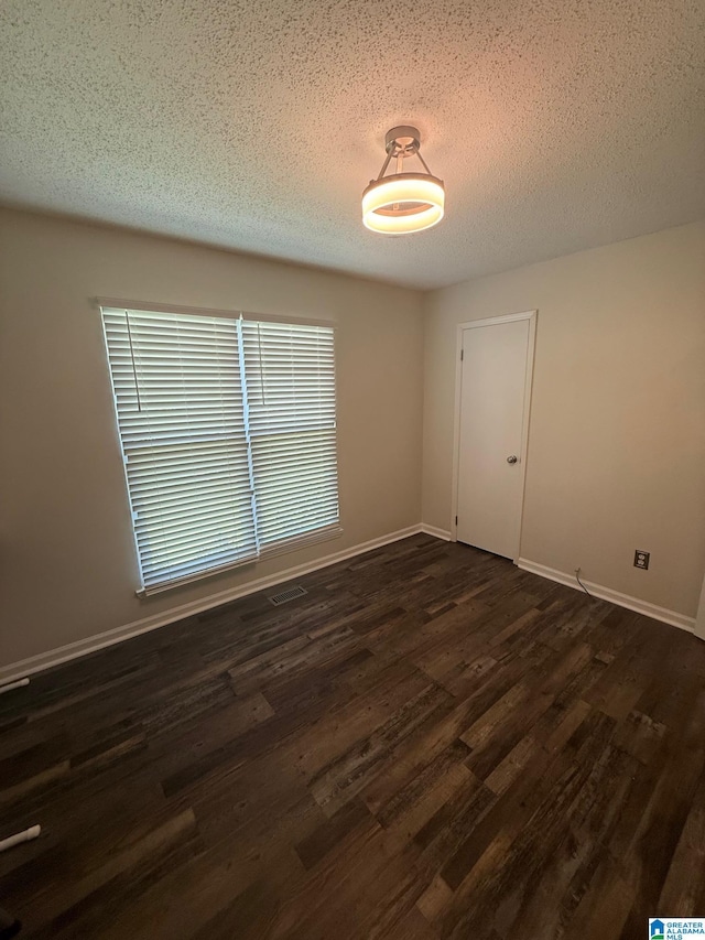 spare room featuring dark wood finished floors, baseboards, and a textured ceiling