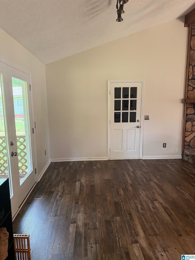 interior space featuring vaulted ceiling, a textured ceiling, dark wood-style floors, and baseboards