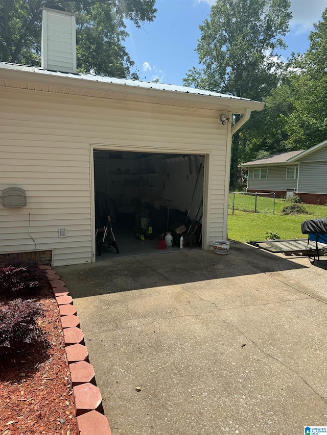 garage with concrete driveway and fence