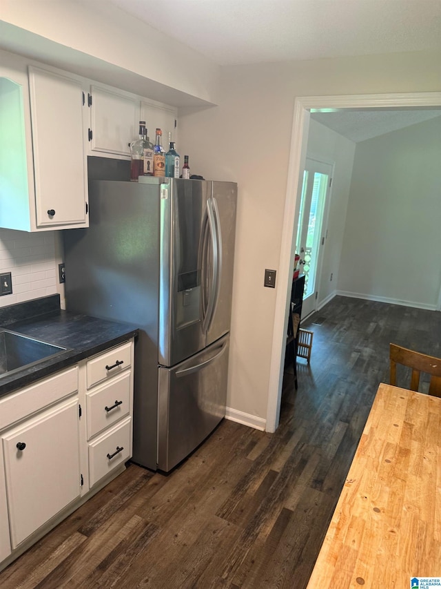 kitchen with dark wood-style flooring, stainless steel fridge, tasteful backsplash, baseboards, and white cabinets