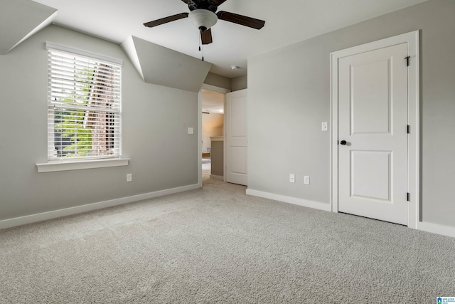 unfurnished bedroom featuring carpet floors, a ceiling fan, baseboards, and vaulted ceiling