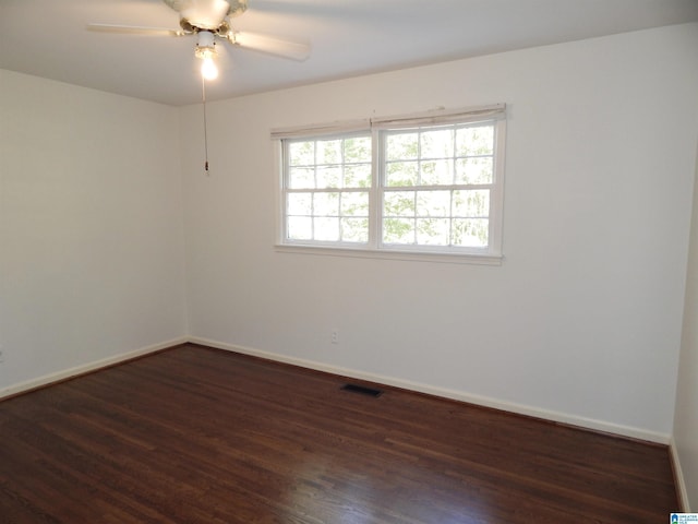 empty room featuring visible vents, a ceiling fan, baseboards, and wood finished floors