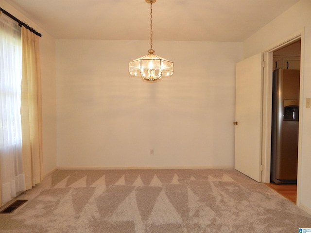 unfurnished room with an inviting chandelier, visible vents, and light colored carpet