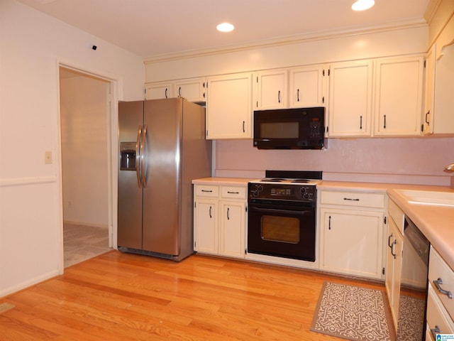 kitchen featuring light countertops, light wood-style flooring, black appliances, and a sink