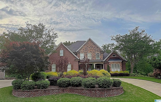view of front of home with curved driveway, a front yard, and stone siding