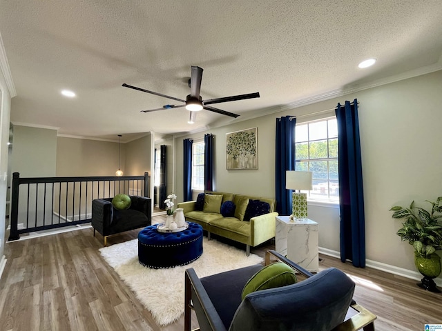living area featuring crown molding, a ceiling fan, wood finished floors, and a healthy amount of sunlight