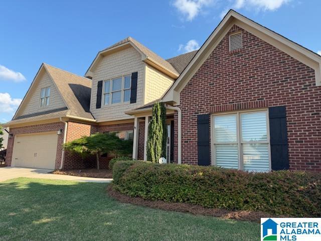 view of front of property with brick siding, driveway, and a front yard
