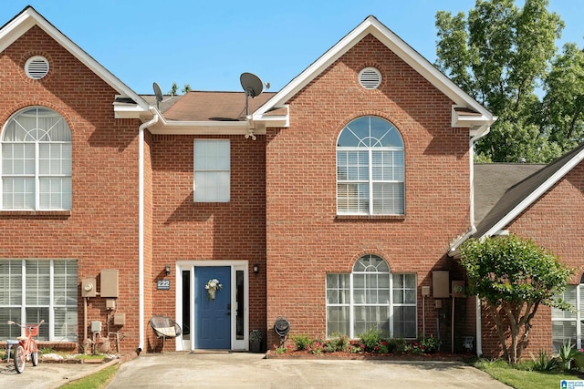 view of front of home with a shingled roof and brick siding