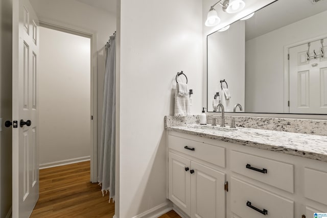 bathroom with baseboards, wood finished floors, visible vents, and vanity
