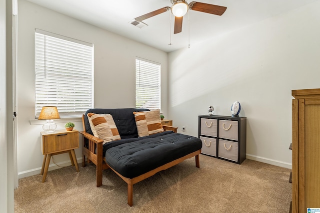 living area featuring visible vents, baseboards, ceiling fan, and light colored carpet