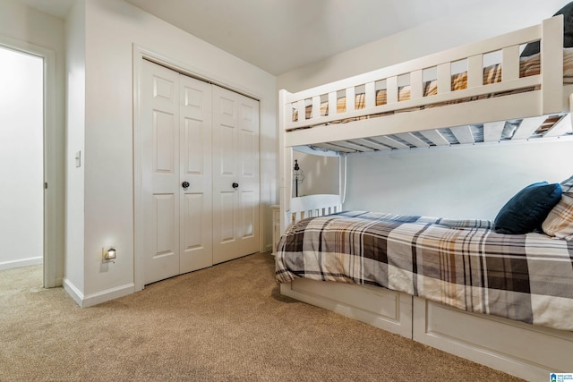 carpeted bedroom featuring baseboards and a closet