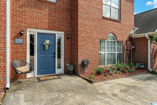 view of exterior entry featuring brick siding and roof with shingles