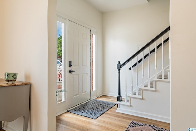 entrance foyer featuring arched walkways, baseboards, a wealth of natural light, and wood finished floors