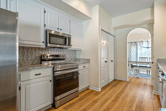 kitchen with light wood finished floors, tasteful backsplash, white cabinetry, and stainless steel appliances