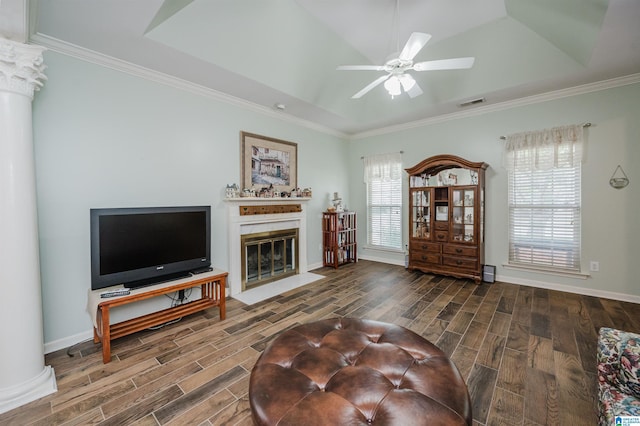 living area with wood finish floors, a fireplace with flush hearth, ornamental molding, and ceiling fan