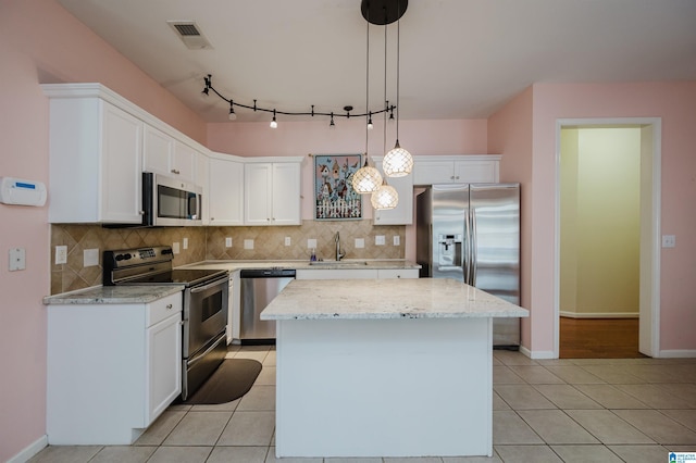 kitchen with a sink, a center island, stainless steel appliances, decorative backsplash, and visible vents