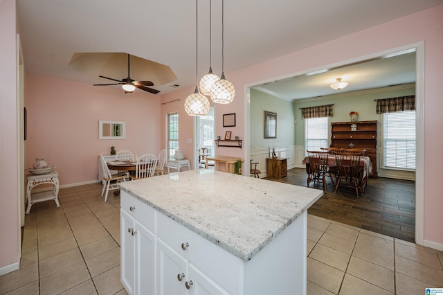 kitchen featuring a center island, white cabinetry, a ceiling fan, light tile patterned floors, and decorative light fixtures