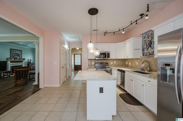 kitchen featuring a fireplace, a center island, a sink, appliances with stainless steel finishes, and backsplash