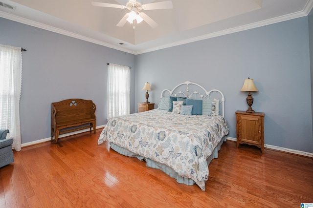 bedroom featuring crown molding, baseboards, wood finished floors, and visible vents