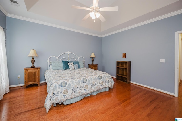bedroom with crown molding, visible vents, wood finished floors, baseboards, and a ceiling fan