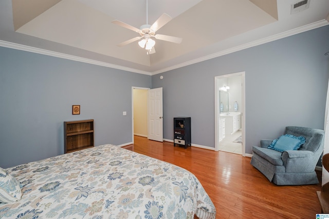 bedroom with visible vents, crown molding, wood finished floors, baseboards, and a tray ceiling
