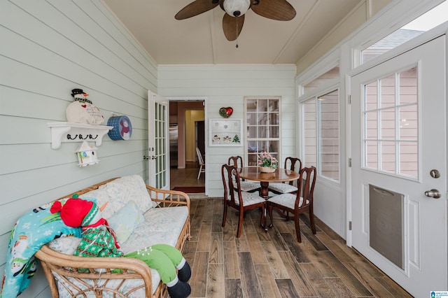 sunroom / solarium with wooden walls, ornamental molding, and wood finished floors