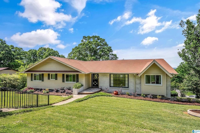 ranch-style house featuring brick siding, a front lawn, roof with shingles, and fence