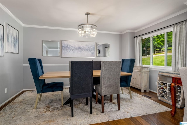 dining room featuring crown molding, baseboards, wood finished floors, and a chandelier