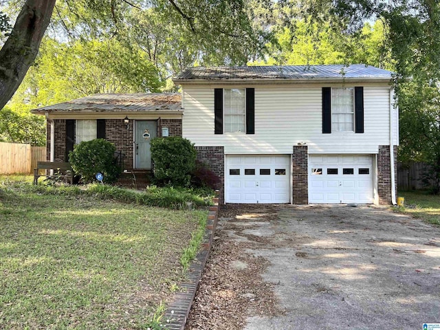tri-level home with a garage, fence, aphalt driveway, and brick siding