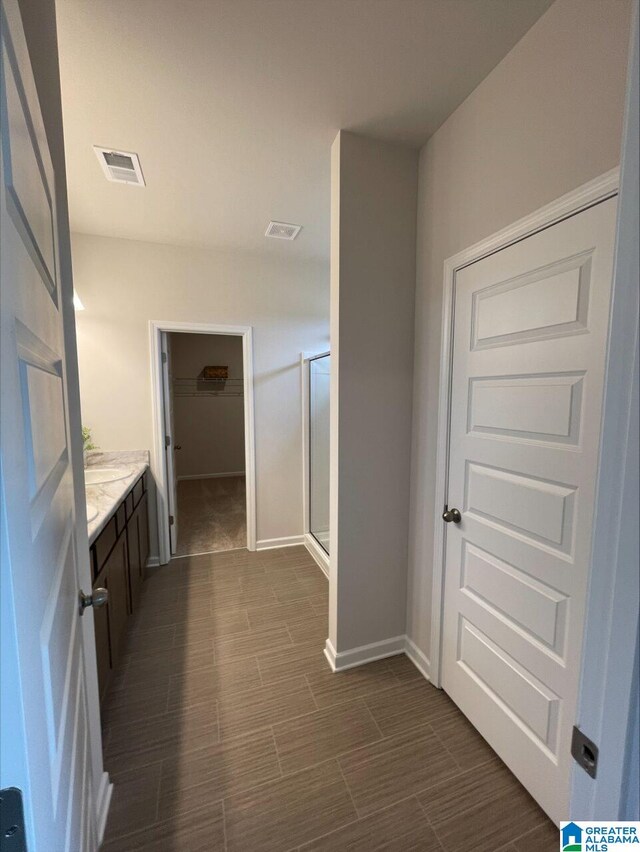bathroom featuring vanity, a stall shower, a spacious closet, and visible vents