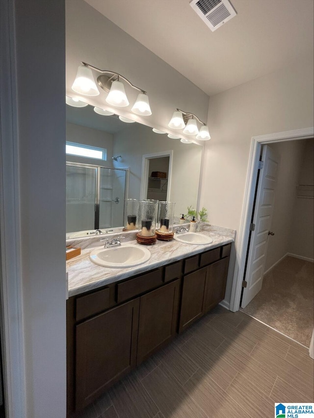 bathroom featuring double vanity, visible vents, a sink, and a stall shower