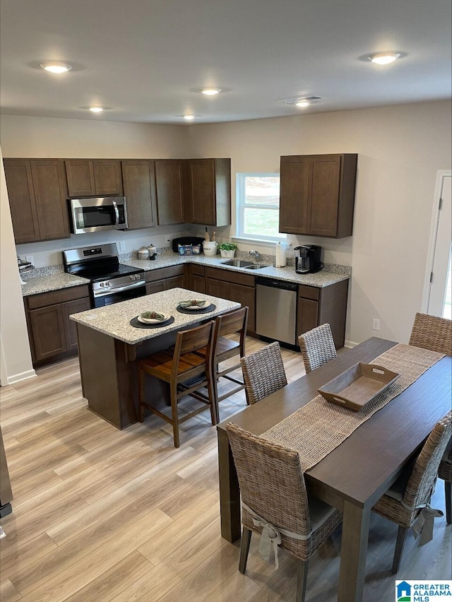 kitchen featuring dark brown cabinets, a sink, light wood finished floors, stainless steel appliances, and recessed lighting