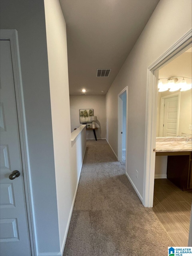 hallway featuring carpet flooring, baseboards, and visible vents
