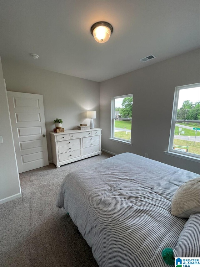 carpeted bedroom with baseboards, multiple windows, and visible vents