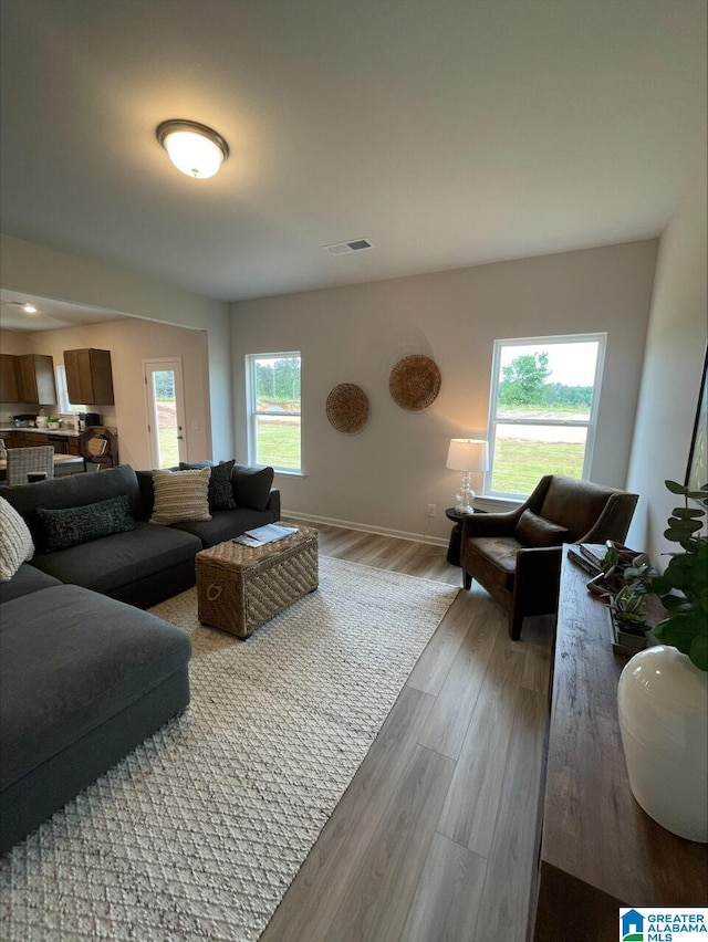 living room with baseboards, visible vents, and light wood finished floors
