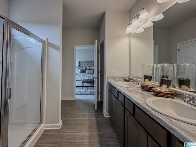 ensuite bathroom featuring a sink, baseboards, a shower stall, and double vanity