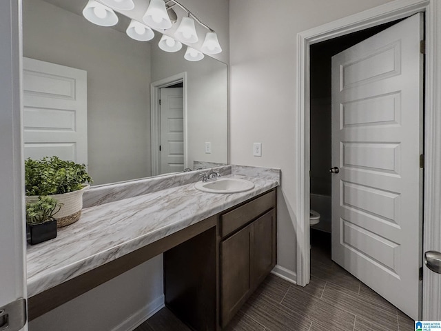 bathroom featuring toilet, baseboards, and vanity