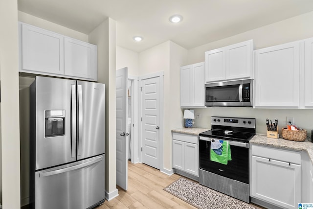 kitchen with light stone countertops, light wood-style flooring, stainless steel appliances, recessed lighting, and white cabinetry