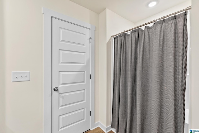 bathroom with a shower with shower curtain and wood finished floors