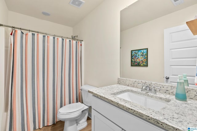 bathroom with visible vents, wood finished floors, toilet, and vanity