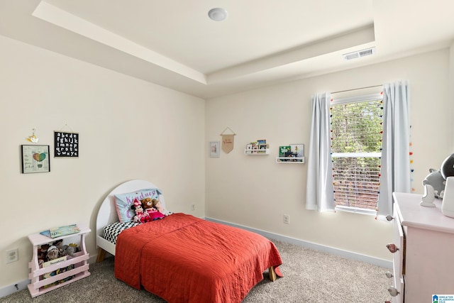 carpeted bedroom featuring a raised ceiling, baseboards, and visible vents