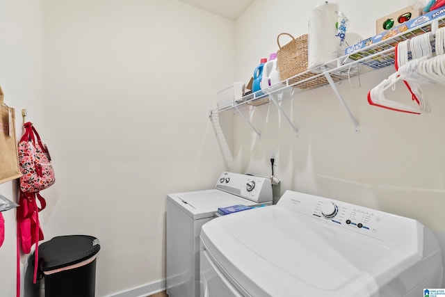 washroom featuring separate washer and dryer, laundry area, and baseboards