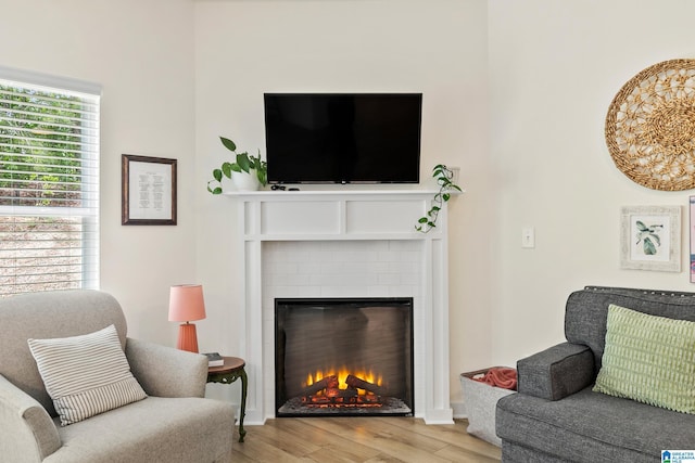 living area with a warm lit fireplace and wood finished floors